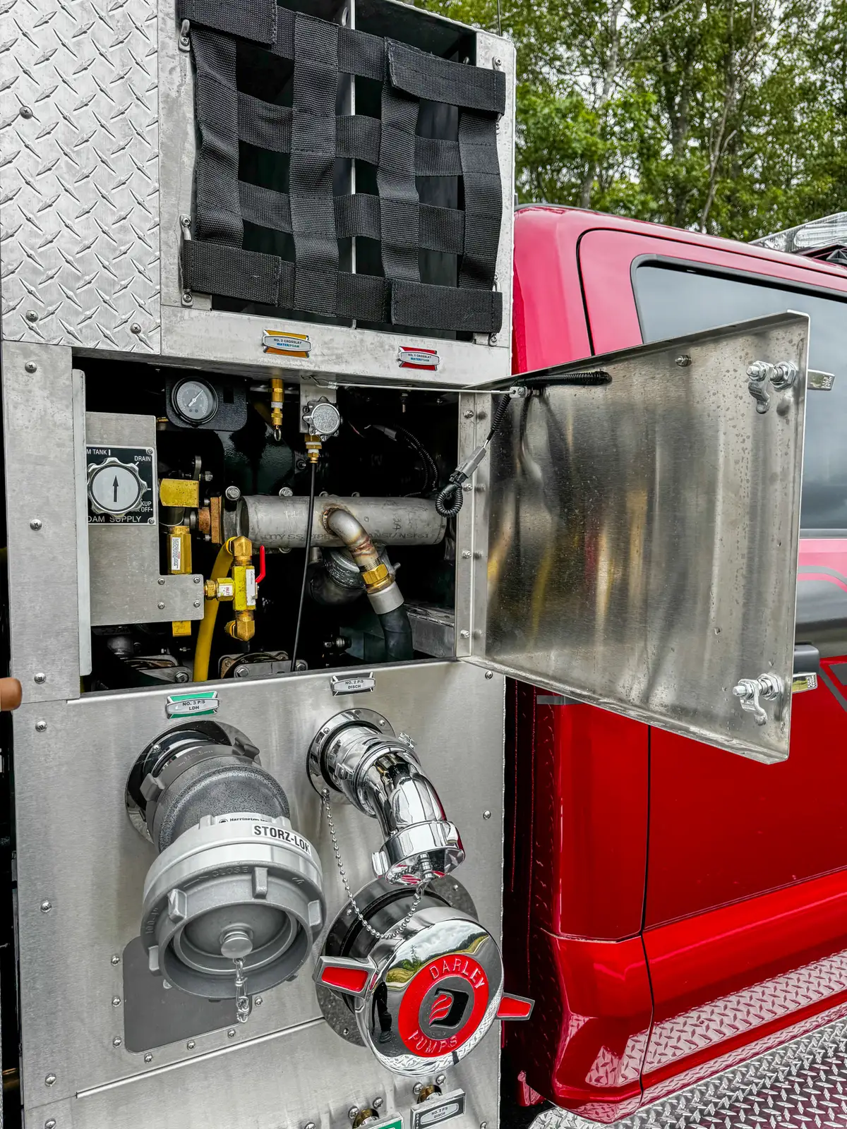 Side plumbing detail with intake hose connection near cab-side panel.